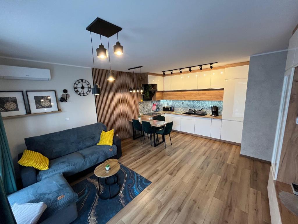 a living room with a blue couch and a kitchen at Apartament Calisia in Kalisz