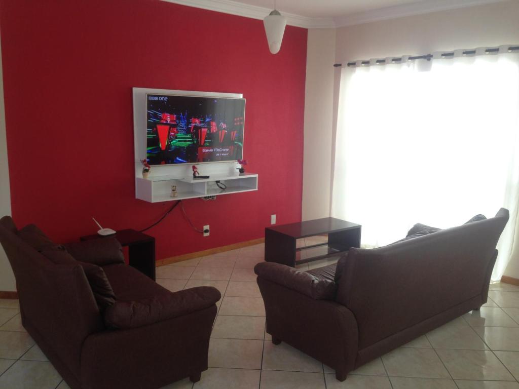 een woonkamer met 2 stoelen en een flatscreen-tv bij Apartamento em Meia Praia in Meia Praia