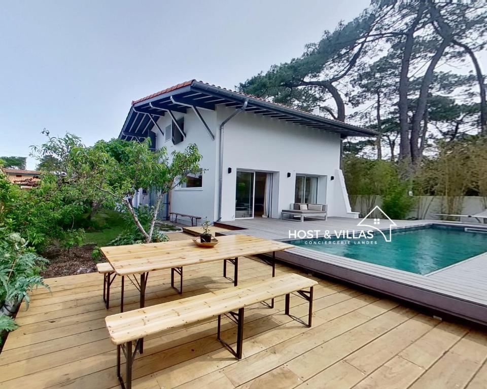 a wooden deck with a picnic table and a house at Host Villas LA TIRMANAISE Capbreton in Capbreton