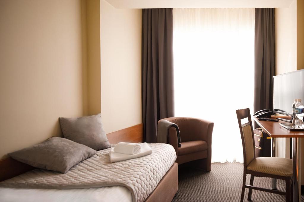 a hotel room with a bed and a desk and a window at HotelsLublin in Lublin