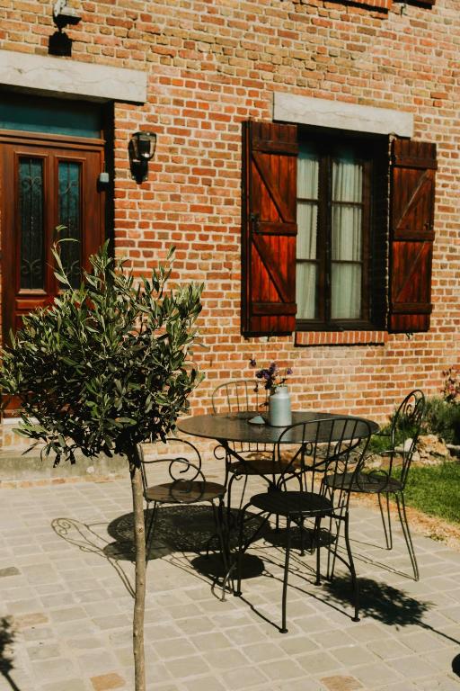a table and chairs in front of a brick building at La batisse du Champ Manneret Maison d'hôte Falaise - logement entier in Falaise