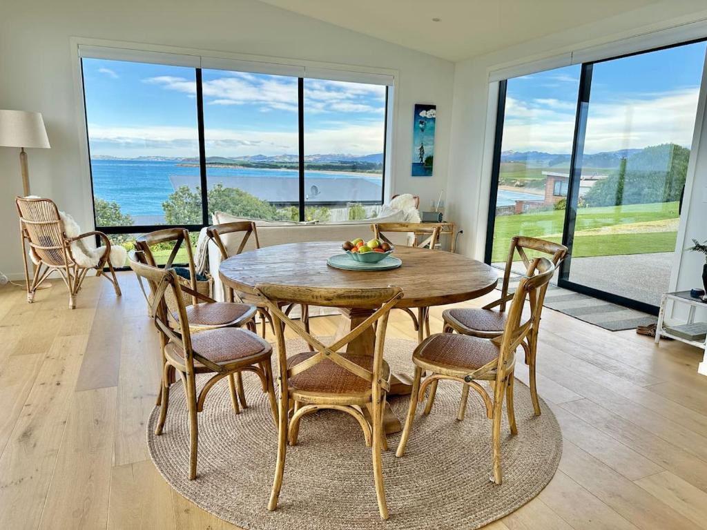 a dining room with a wooden table and chairs at Coastal Luxe Villa in Kakanui