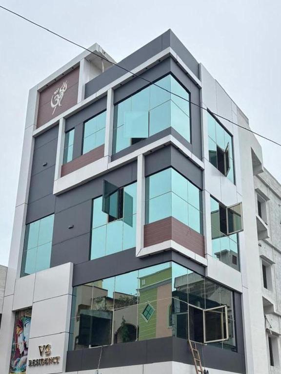 a tall building with glass windows on it at VS Residency in Elūru