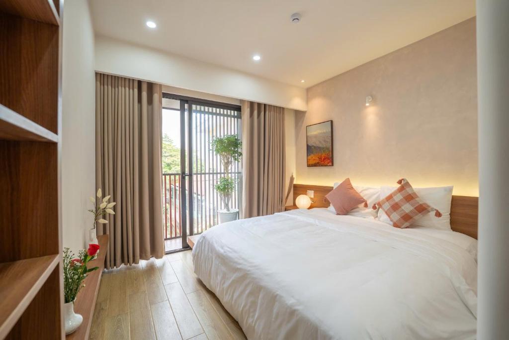 a bedroom with a large bed and a large window at MIRO Homestay in Hue