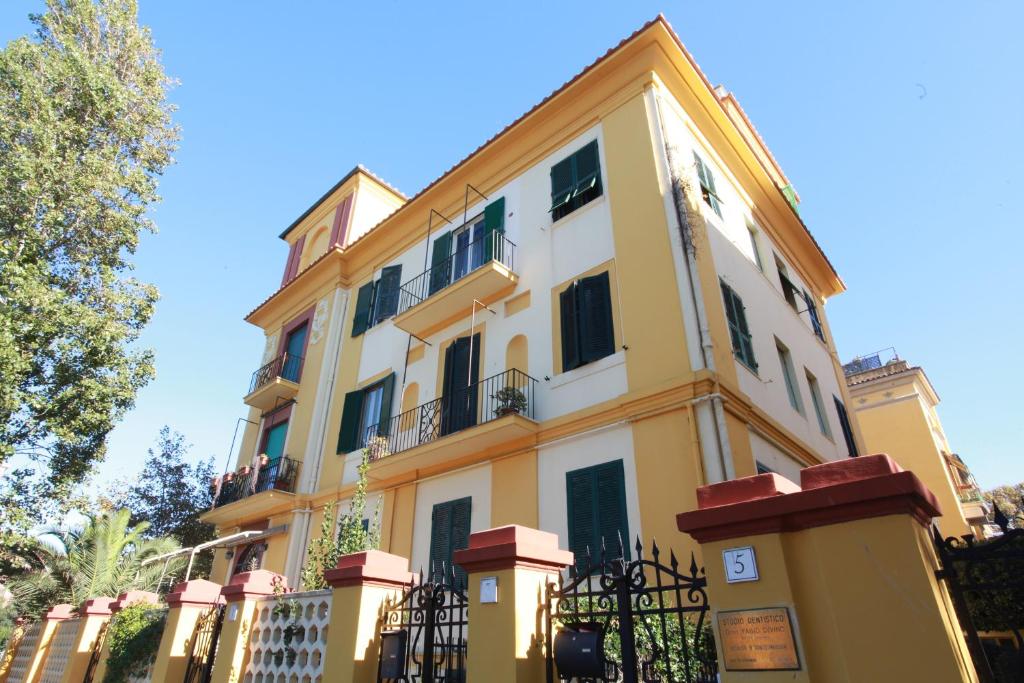 un edificio blanco y amarillo con una valla en Lido di Ostia 1933, en Lido di Ostia