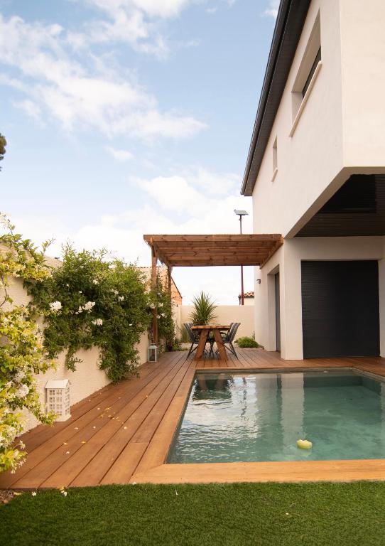 a deck with a table and a picnic table on a house at Villa au calme avec piscine privée - Lac de Jouarres in Olonzac