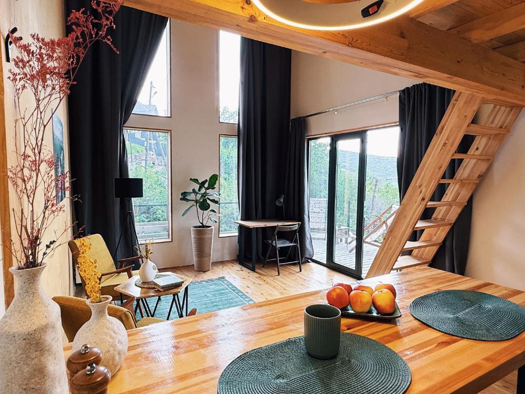 a living room with a wooden table and a staircase at Alexa Mountain Homes in Kok-Shoky