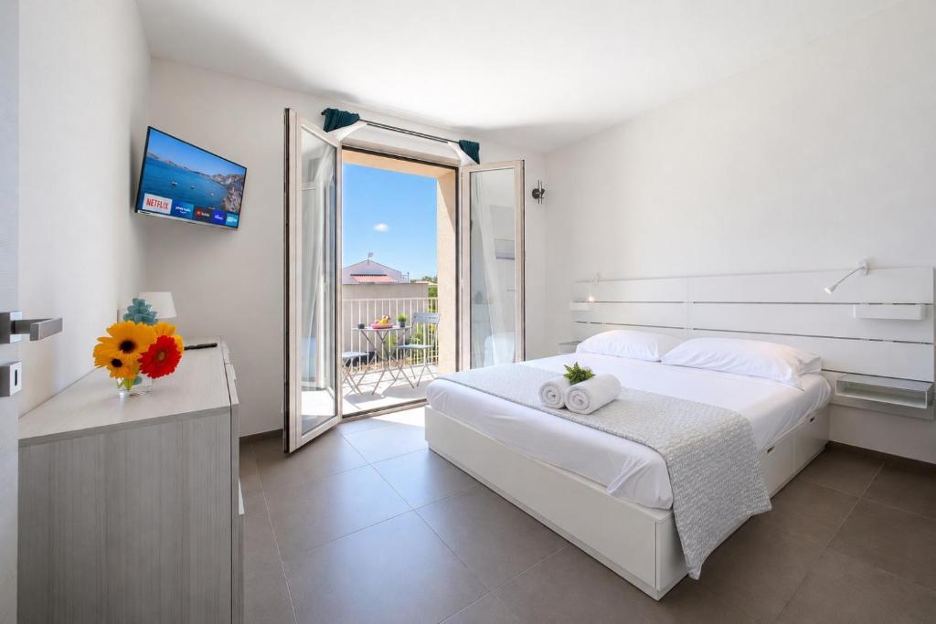 a white bedroom with a large bed and a balcony at 18 Gradi Apartments in Birgi Vecchi