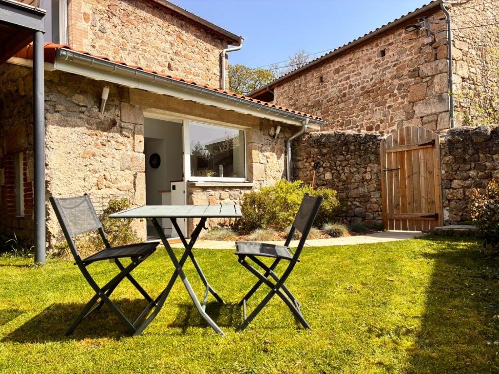 a picnic table and two chairs in a yard at Superbe appartement avec jacuzzi et jardin privé in Marlhes