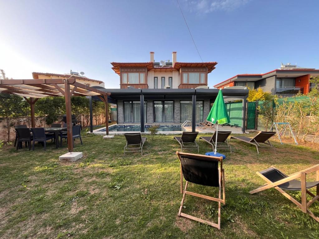 a yard with chairs and tables and a house at Derya Beach Agullu Villa 5 in Kaş