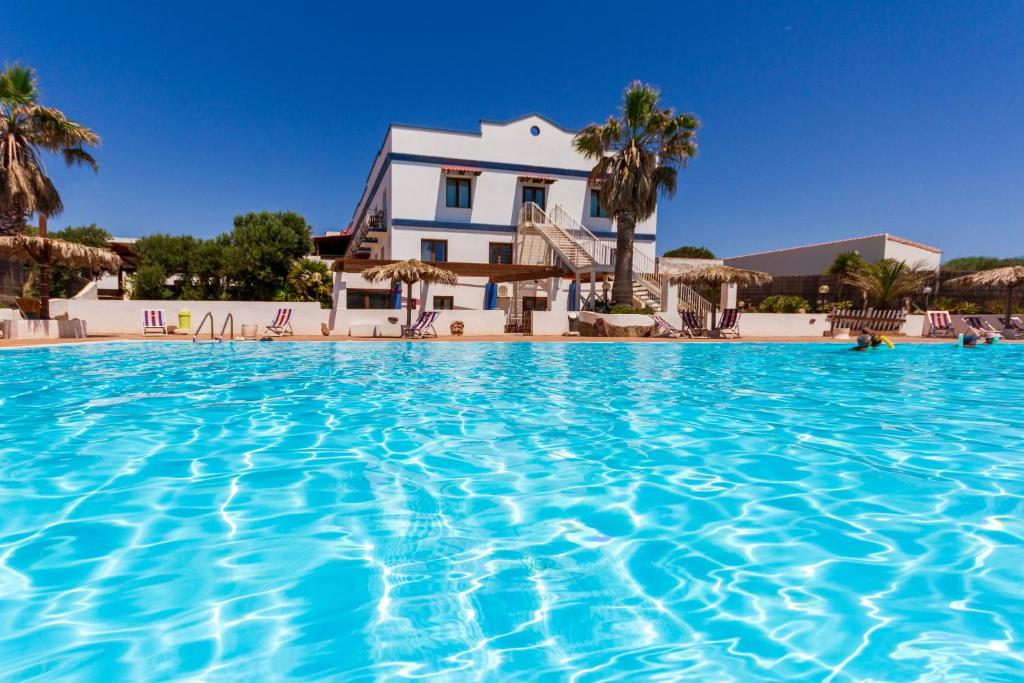 a large swimming pool in front of a house at Hotel Stella Del Sud in Calasetta