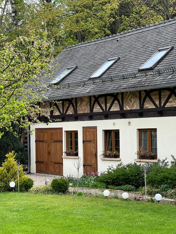 a white house with wooden doors and windows at Dom Gościnny Leniuchy in Leśna