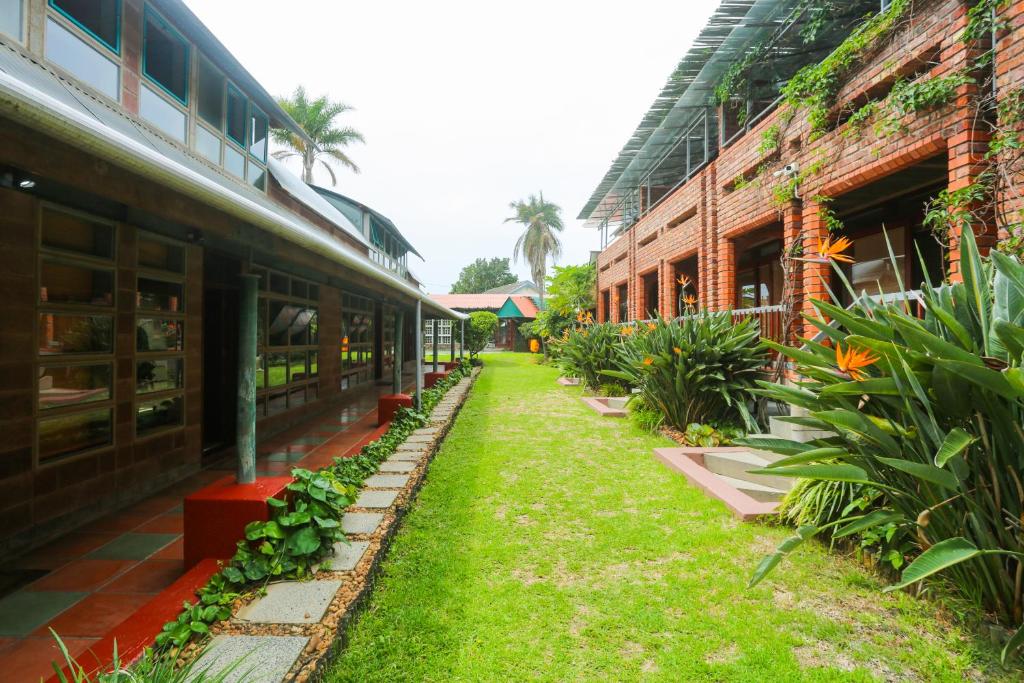 a walkway between two buildings with green grass and plants at Asali Lodge in East London