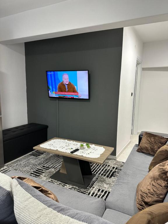 a living room with a couch and a tv on a wall at AirbnbTzo in Perístasis