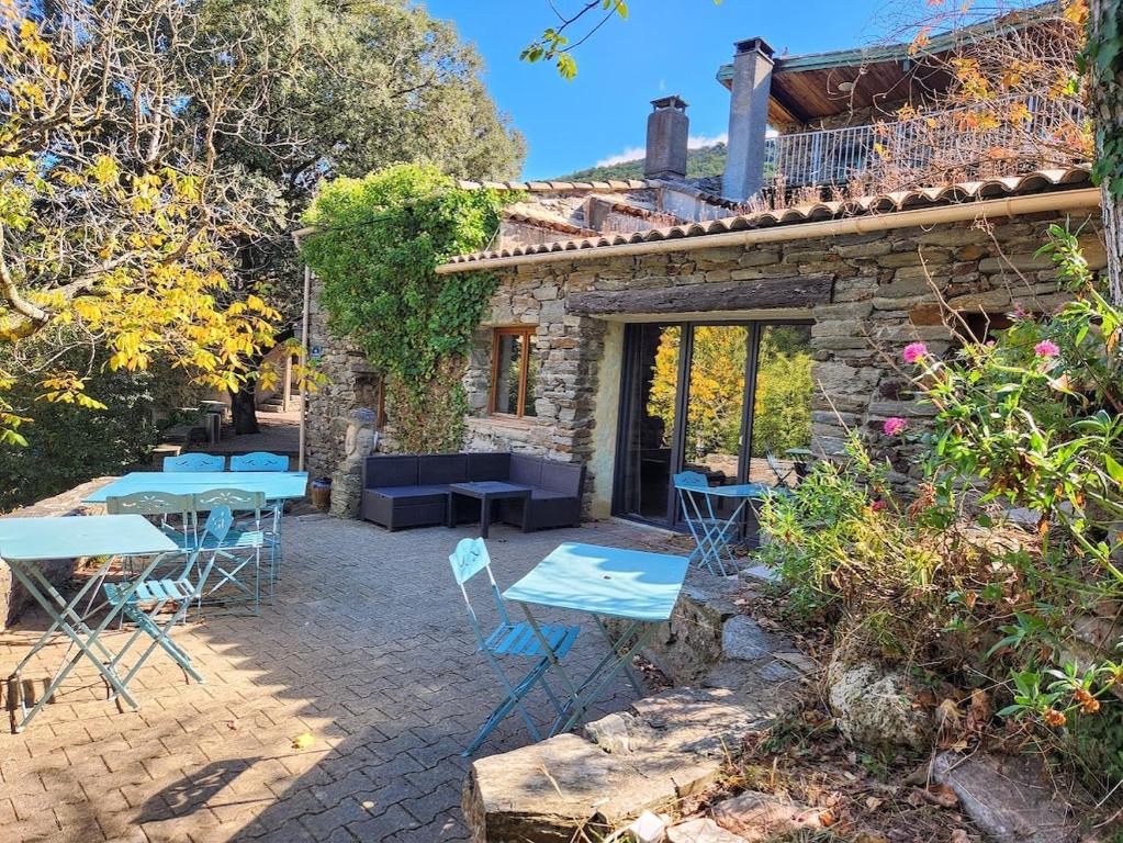 a patio with tables and chairs in front of a stone house at Grand Gite des Jourdets in Lairière