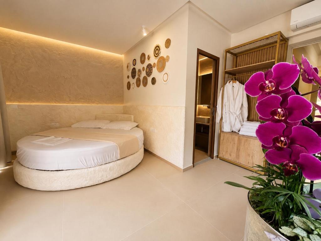 ein Schlafzimmer mit einem Bett in einem Zimmer mit lila Blumen in der Unterkunft Blue Mill Resort, Sarande in Mesopotam