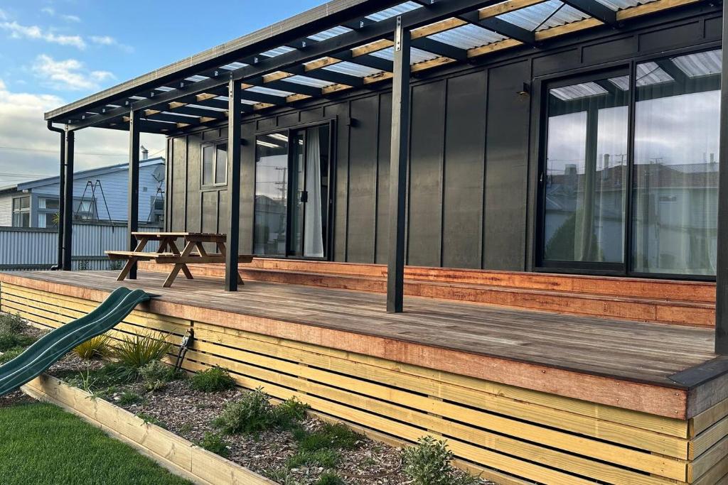 a house with a wooden deck with a picnic table at Settlers Nook Oamaru in Oamaru