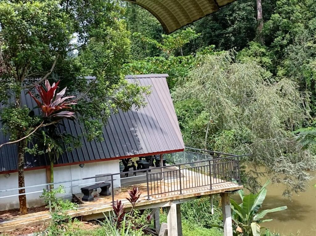 a house with a wooden deck next to a river at Rainforest River Cabana & Villa in Deniyaya