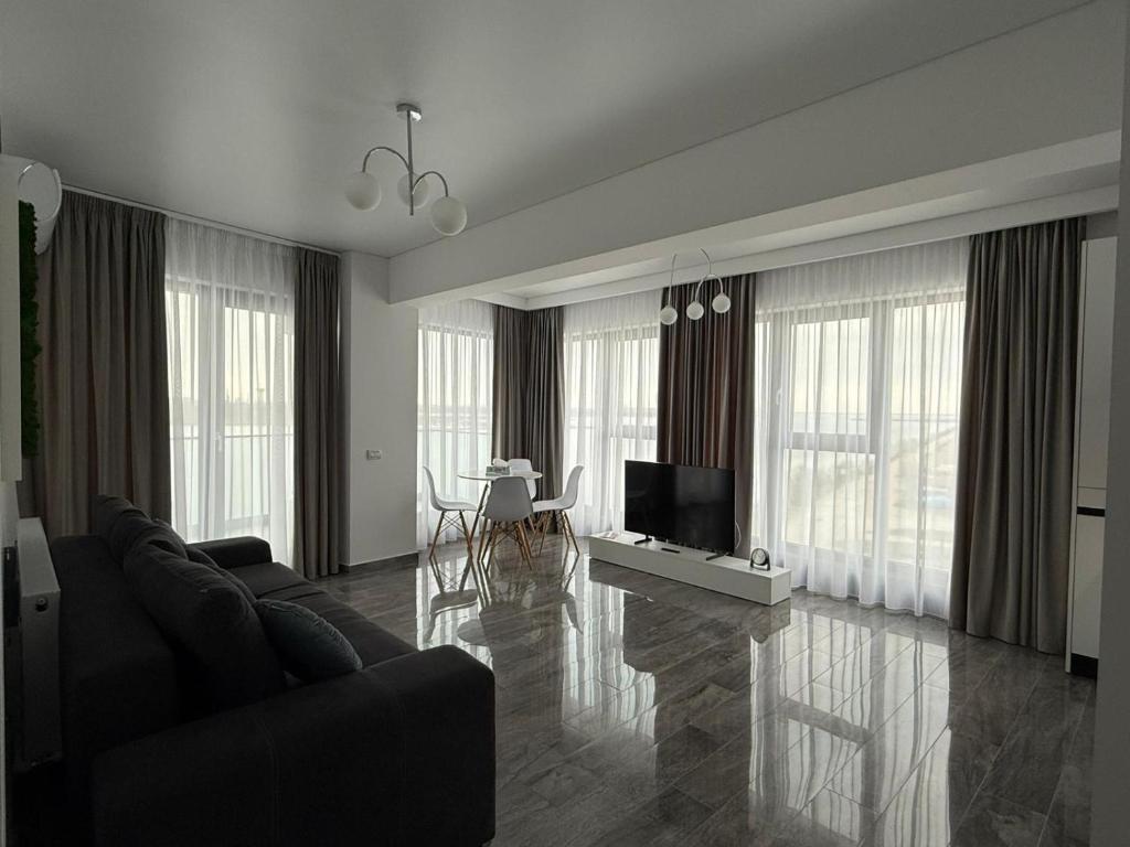 a living room with a couch and a television at Seaside Escape - Luxury Apartment in Năvodari