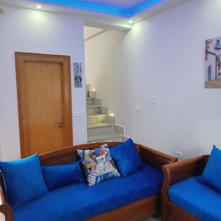 a living room with a blue couch and stairs at Littlhouse in Rafrāf