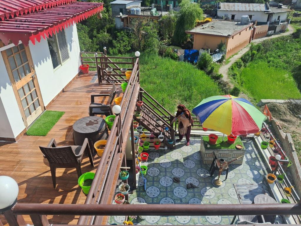 a woman standing on a deck with an umbrella at Nilkanth gest hause in Mukteshwar