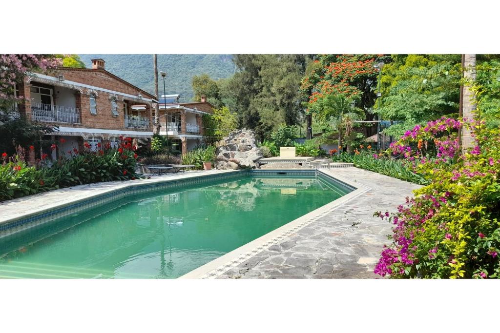 a swimming pool in a yard with flowers at Capital O Posada Del Pescador Jocotepec in Chapala