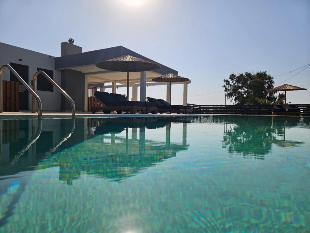 ein Schwimmbad mit einigen Stühlen und ein Haus in der Unterkunft Mat Suites in Lachania