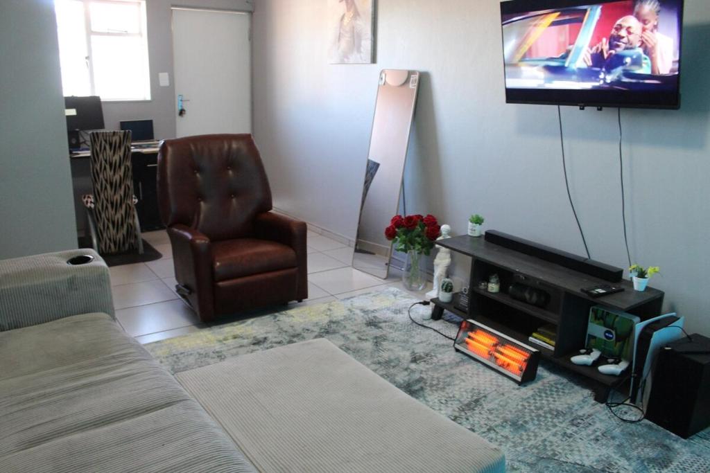 a living room with a couch and a tv and a chair at Penthouse in Bloemfontein