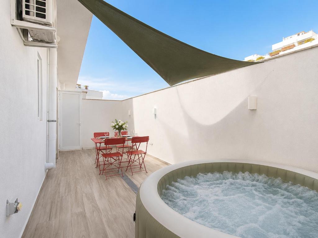 a bathroom with a tub and a table on a balcony at Large 3-Bedroom with Jacuzzi near St Julians in Is-Swieqi