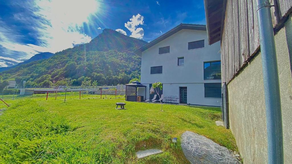 a building with a grassy yard next to a mountain at Appartement 2,5 pièces et SPA in Chamoson