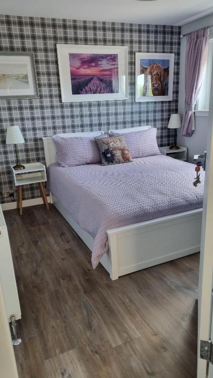 a bedroom with a large bed with purple pillows at Innisfail Edi - double room with private bathroom in Edinburgh