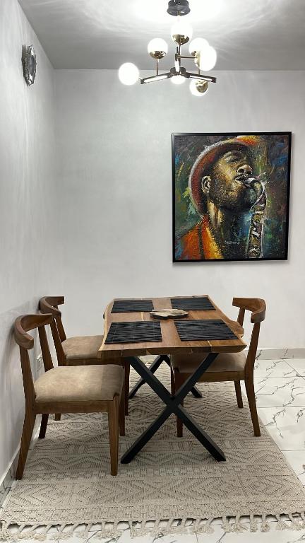 a dining room with a table and a painting on the wall at Olivewood Apartments in Ankuru