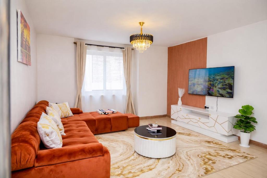 a living room with a couch and a tv at Stylish 2BR Apartment Free WiFi Near Nairobi National Park in Ongata Rongai 