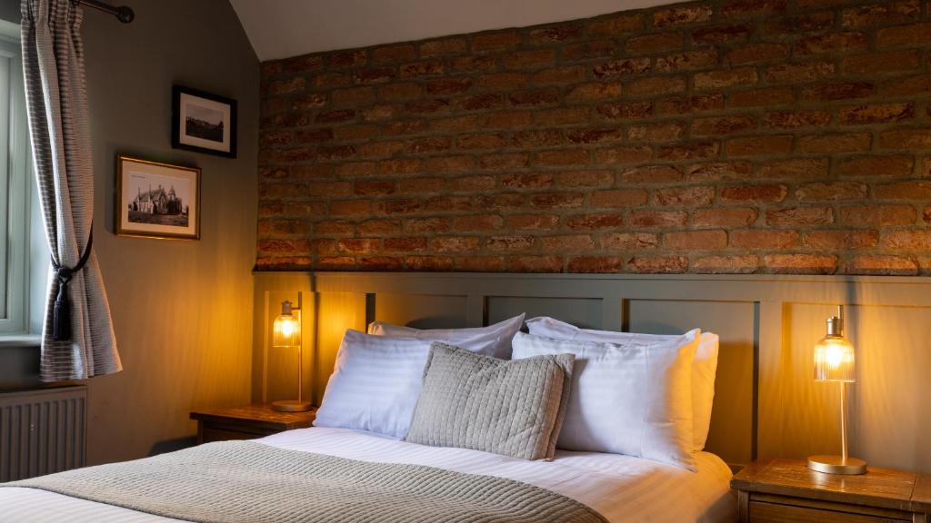 a bedroom with a brick wall and a bed with pillows at The Poacher Inn in Upton Grey