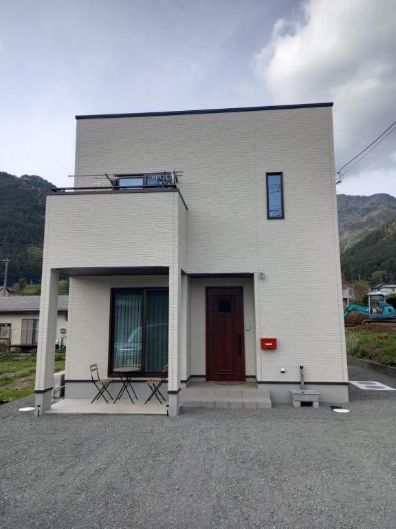 a white building with a door and a bench in front at ミエル富士 in Oishi
