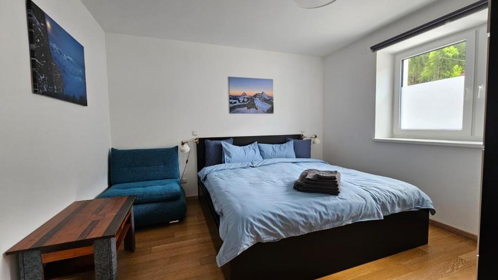 a bedroom with a bed and a blue chair at Ski & Sky Apartment in Hinterstoder