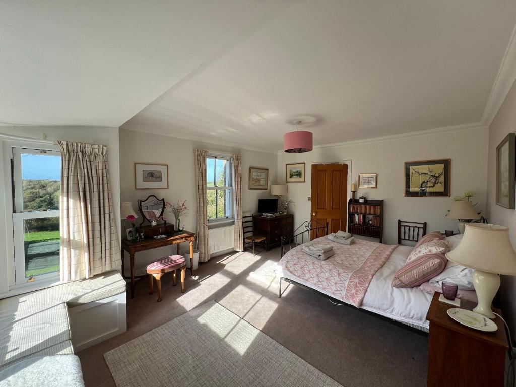 a bedroom with a bed and a desk and a window at Elmsleigh in Marhamchurch