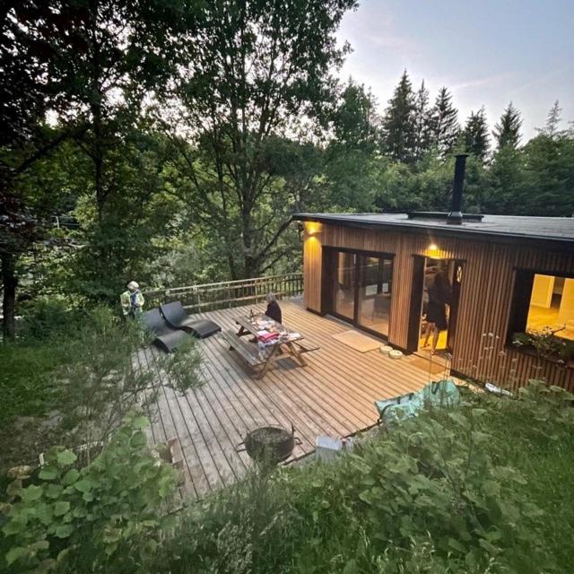 a small cabin with a deck with a table and chairs at Deep Forest in Bastogne