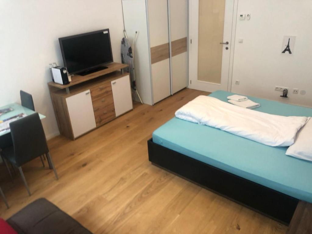 a room with a bed and a desk with a television at Tayfun-Living in Vienna