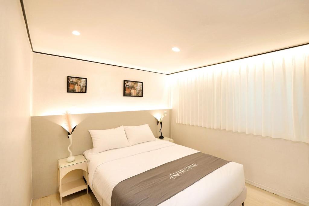 ein Schlafzimmer mit einem großen weißen Bett und zwei Lampen in der Unterkunft AvIENNE 홍대 명동 이태원 DDP KSPO 경북궁 롯데월드 성수 in Seoul