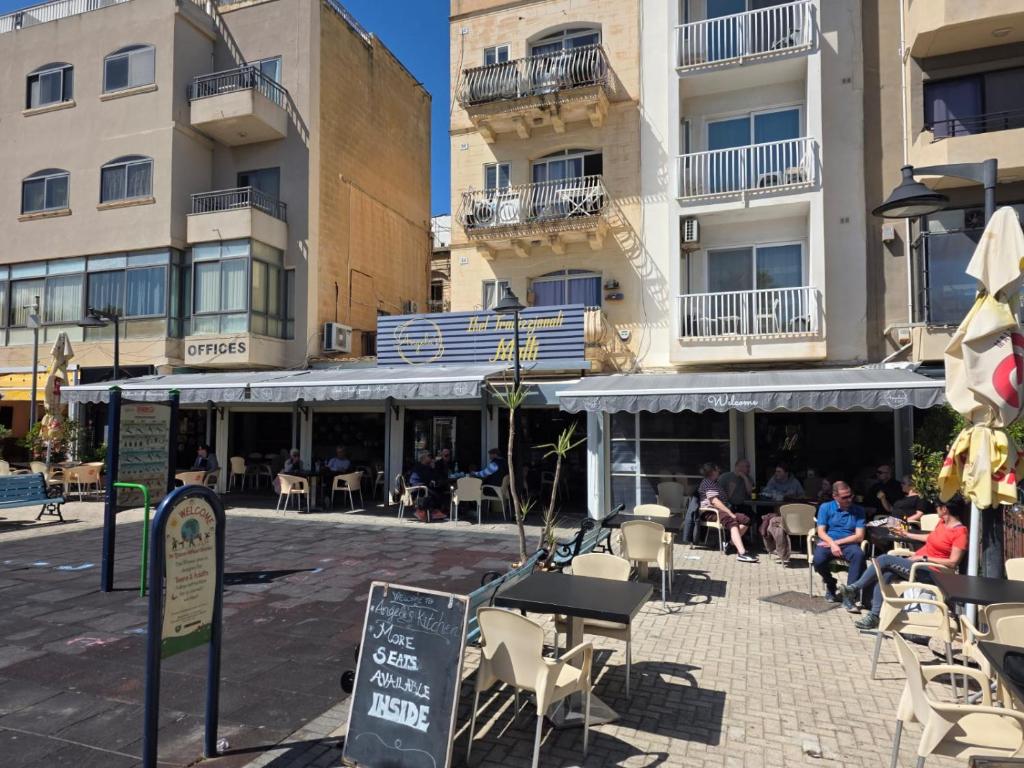 a group of people sitting outside of a building at EJ&A Coastal Suites in Marsaskala