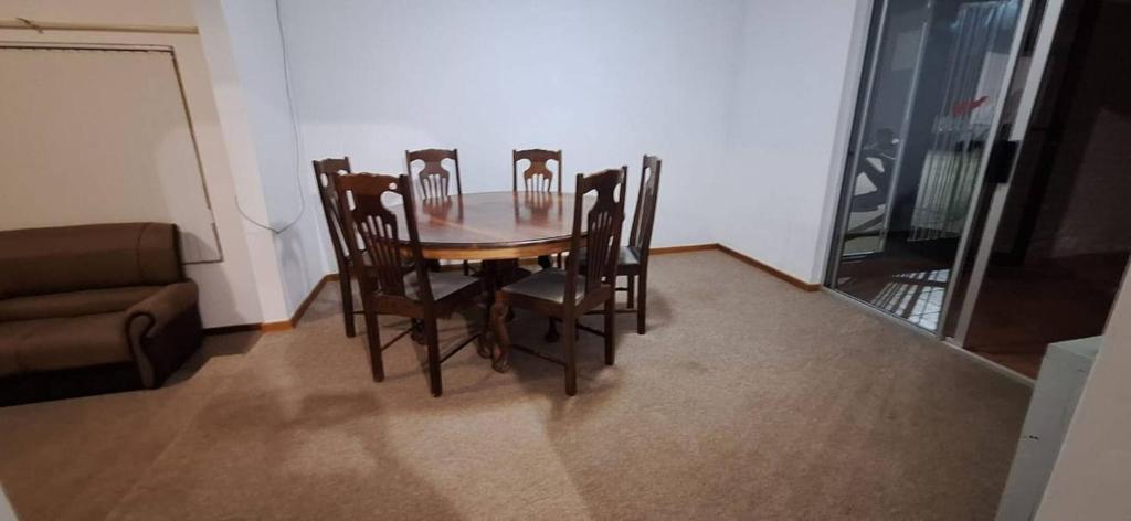 a dining room table with four chairs and a couch at HL Self-catering Accommodation in Bonnievale