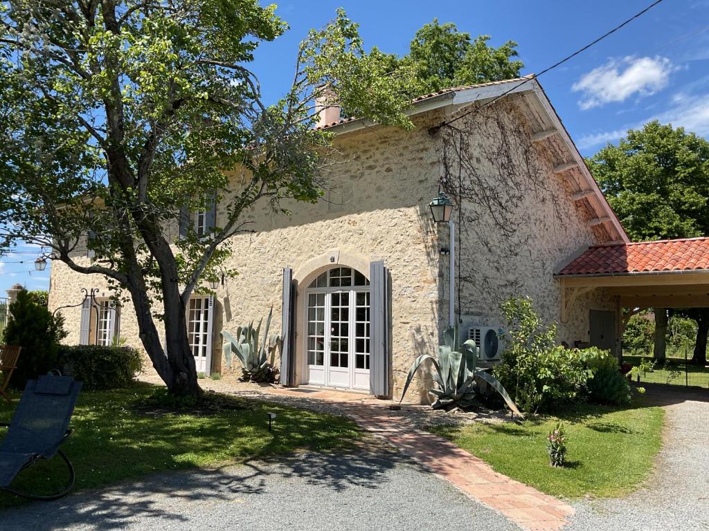 a house with a white door and a tree at Maison en pierre cosy chez Laëtitia in Auros