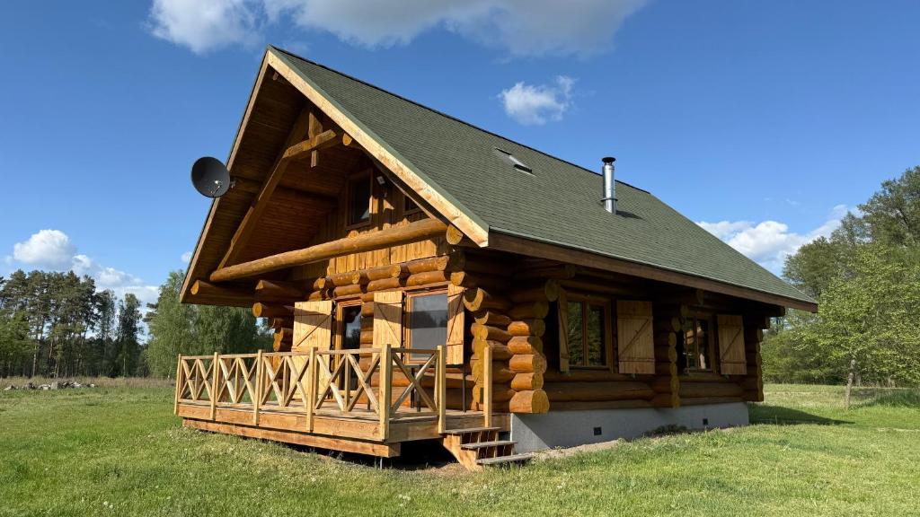 a log cabin with a black roof on a green field at Domy z Bali nad jeziorem - Leśna Oaza in Międzyrzecz