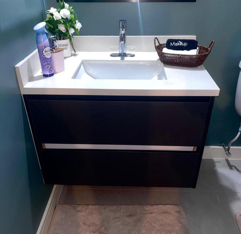 a bathroom vanity with a sink and a basket of flowers at Palistic Paradise luxury private jacuzzi in Portmore