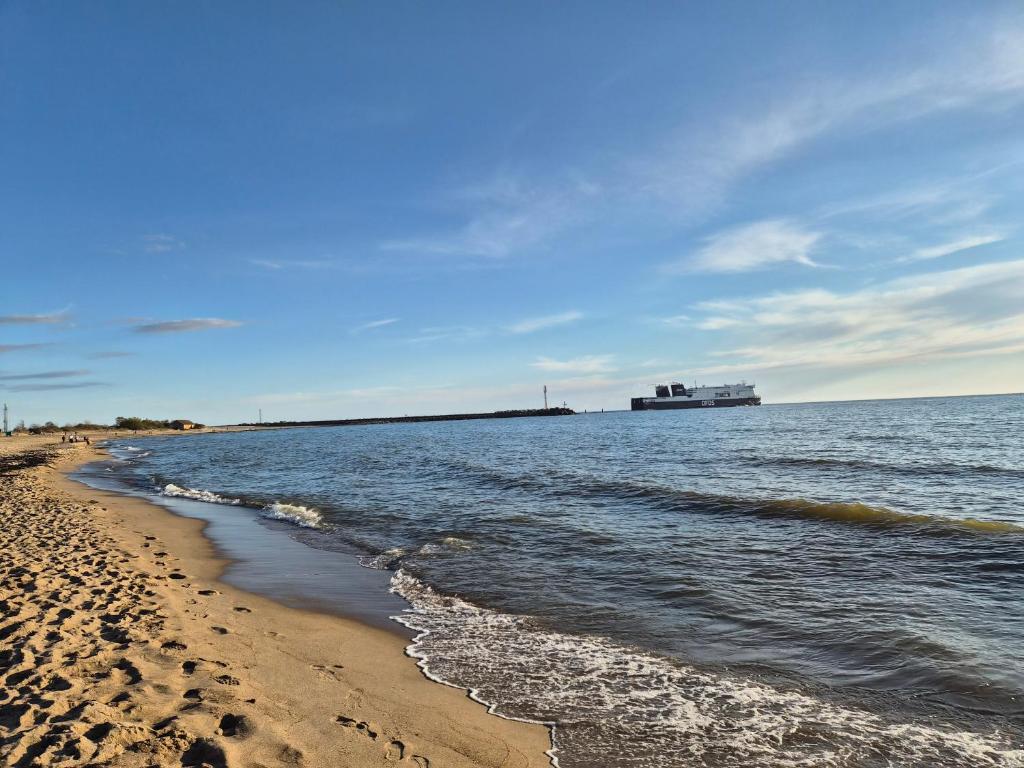 a beach with a cruise ship in the water at Melnragė in Melnragė