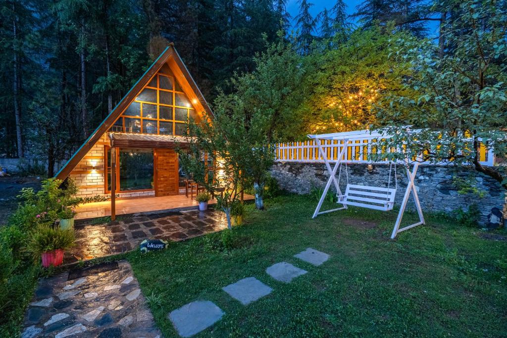 a house with a porch and a swing in the yard at The Social Stays Kasol in Kasol