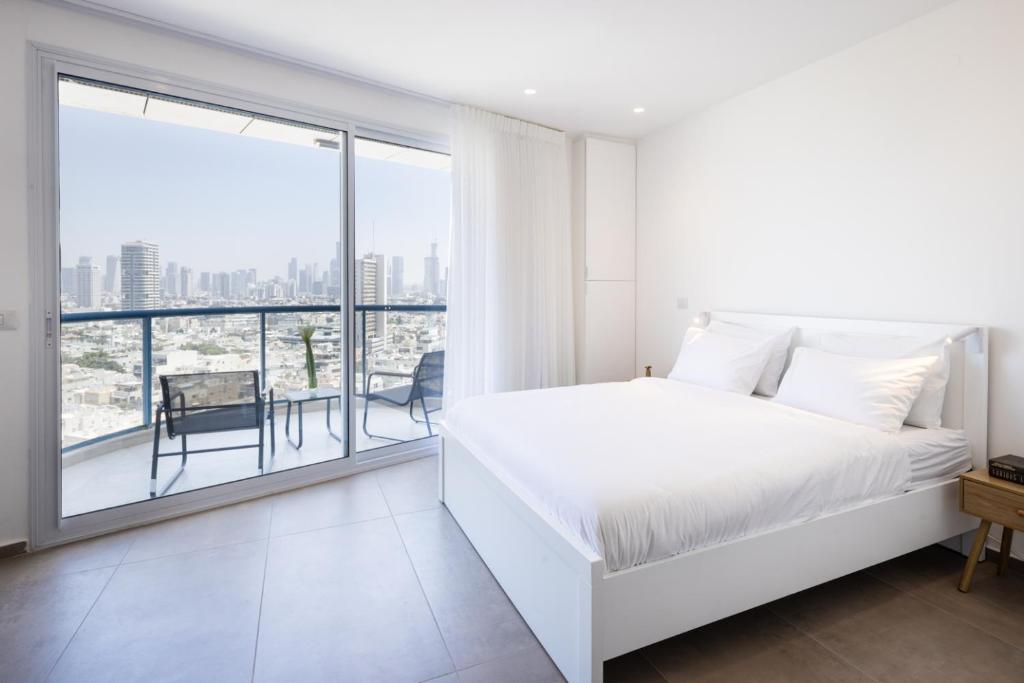 a white bedroom with a bed and a large window at Superb Beachfront Apartments with Shelter by Sea N' Rent in Tel Aviv