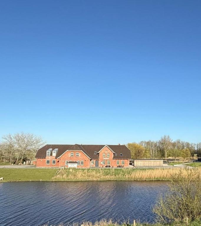 a large brick house next to a body of water at Gaststätte Bongsiel 'Dat Swarte Peerd' in Ockholm