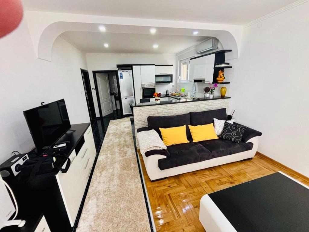 a living room with a black couch and a kitchen at The Olive Tree Apartment in Ljubuški